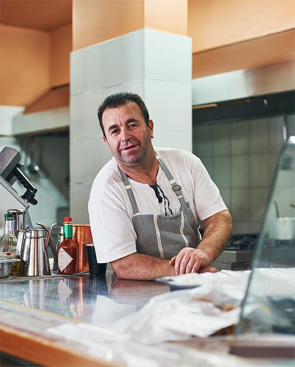 Older man in cafe leans across counter