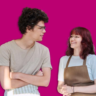 Two hospitality staff in aprons talking to each other