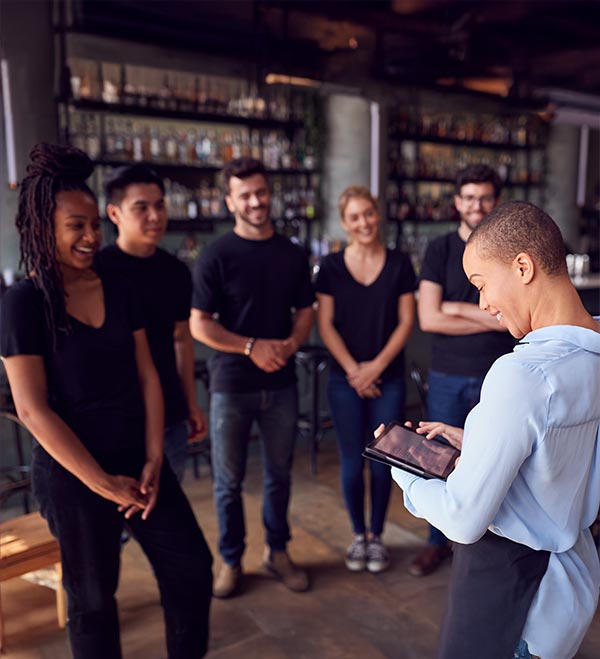 Restaurant owner meeting with young staff checks her tablet